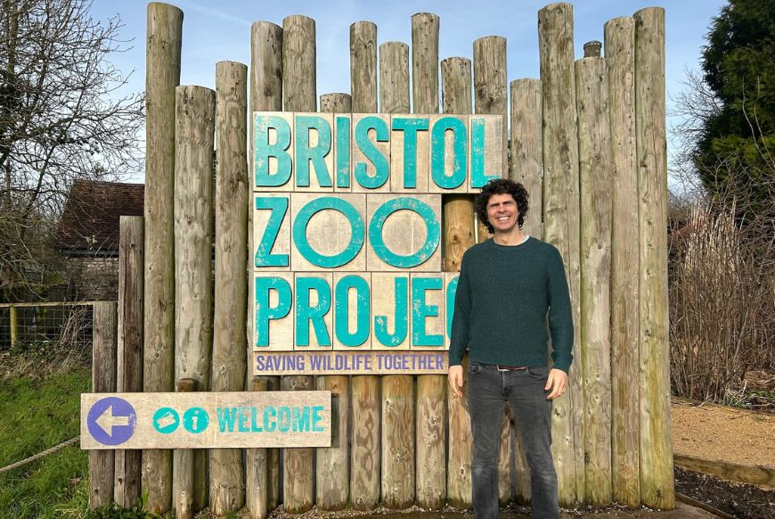 man (andy) standing in front of sign for Bristol zoo project